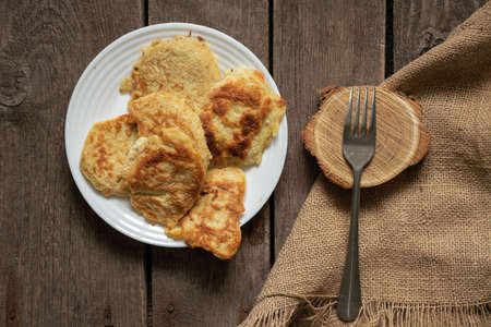 homemade fried pancakes on a white plate for lunch on an old wooden table at home in the kitchenの写真素材