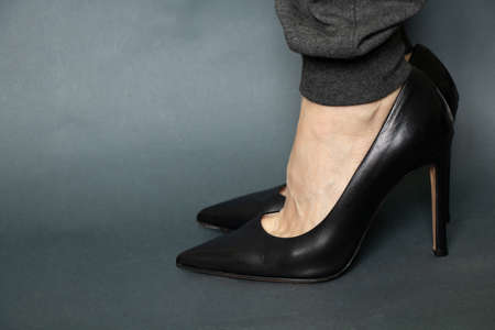 girl in gray sweatpants and leather shoes black high heels on isolated blue backgroundの写真素材