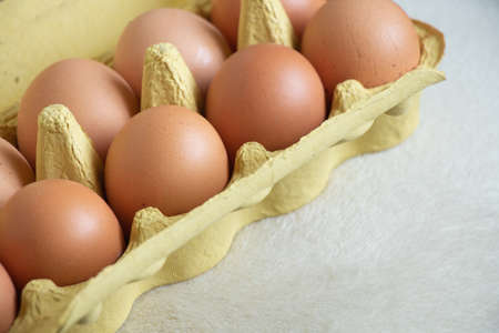 box with yellow chicken eggs on a white background close up
