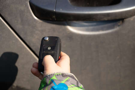 close-up of a child's hand holding a key to a family car on the streetの写真素材