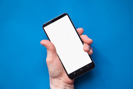 phone with a white screen in the hands of an elderly woman on the table close-up, white screen on the phoneの写真素材