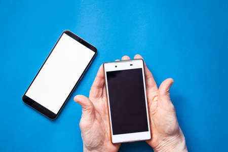 phone with a white screen in the hands of an elderly woman on the table close-up, white screen on the phoneの写真素材
