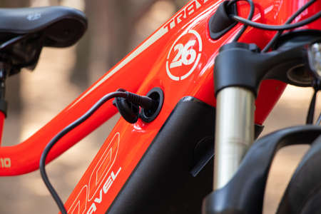 Ukraine Dnipro 05.04.2021 - a red electric bike is recharged in a forest in a park, new technologies, an electric bikeのeditorial素材