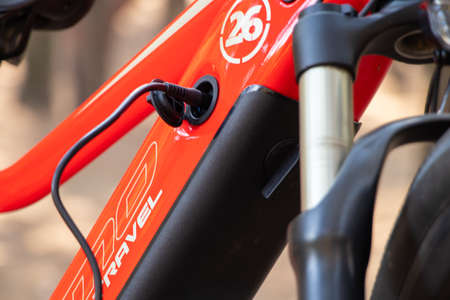 Ukraine Dnipro 05.04.2021 - a red electric bike is recharged in a forest in a park, new technologies, an electric bikeのeditorial素材