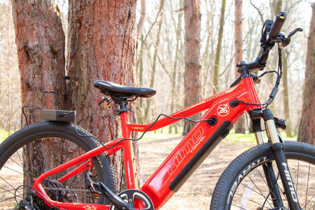 Ukraine Dnipro 05.04.2021 - a red electric bike is recharged in a forest in a park, new technologies, an electric bikeのeditorial素材