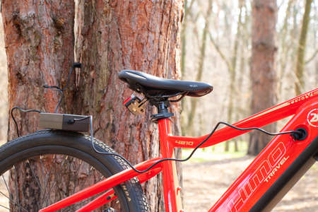 Ukraine Dnipro 05.04.2021 - a red electric bike is recharged in a forest in a park, new technologies, an electric bikeのeditorial素材