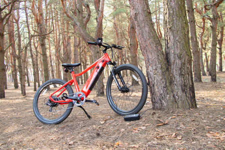 Ukraine Dnipro 05.04.2021 - a red electric bike is recharged in a forest in a park, new technologies, an electric bikeのeditorial素材