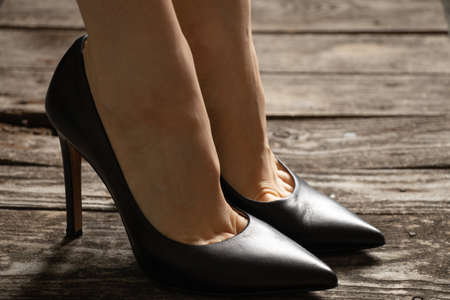 female feet in black leather high-heeled shoes on old wooden floor, womens shoesの写真素材