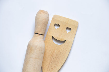 wooden kitchen spatula with smile and rolling pin on isolated white background