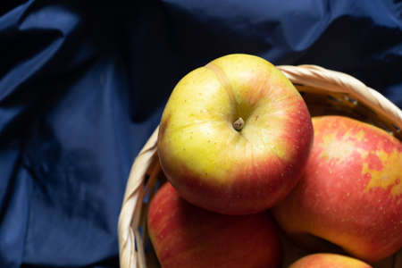 red ripe apples lie on a dark blue cloth close-up