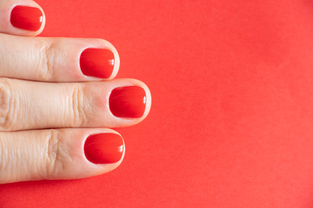 female hands with red manicure close up on isolated colored backgroundの写真素材