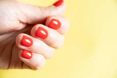 female hands with red manicure close up on isolated colored backgroundの写真素材