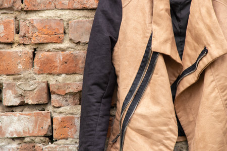 brown womens jacket hanging on hangers on a brick old wall at home on the street, womens fashionの写真素材