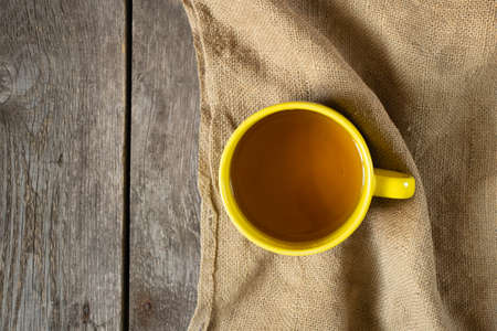 yellow large cup of tea stands on sacking on the table close-upの写真素材