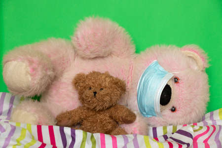 medical mask on a teddy bear that sits on the bed, children get sick, sickの写真素材