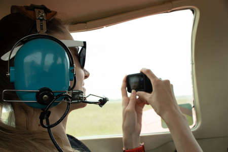a girl in the cabin of a small plane flies over the city and records a video on a camera, a girl in the cabin of an airplaneの写真素材