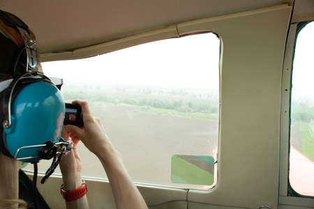 a girl in the cabin of a small plane flies over the city and records a video on a camera, a girl in...