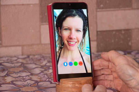 a young girl is talking on a video call from the phone with her family at home, video chat with her family, video conferenceの写真素材