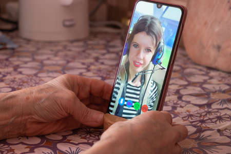 a young girl is talking on a video call from the phone with her family at home, video chat with her family, video conferenceの写真素材