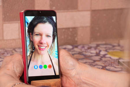 a young girl is talking on a video call from the phone with her family at home, video chat with her family, video conferenceの写真素材