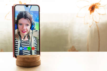 a young girl is talking on a video call from the phone with her family at home, video chat with her family, video conferenceの写真素材