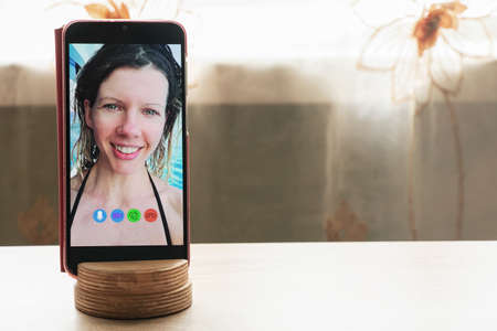 a young girl is talking on a video call from the phone with her family at home, video chat with her family, video conferenceの写真素材