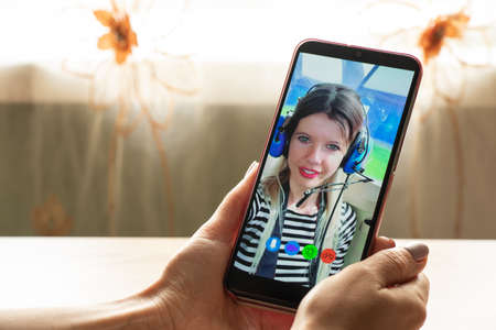 a young girl is talking on a video call from the phone with her family at home, video chat with her family, video conferenceの写真素材