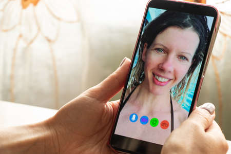 a young girl is talking on a video call from the phone with her family at home, video chat with her family, video conferenceの写真素材