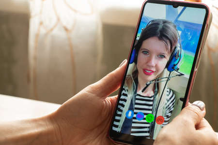 a young girl is talking on a video call from the phone with her family at home, video chat with her family, video conferenceの写真素材