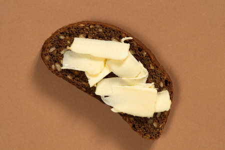 slice of black bread with butter on isolated colored paper background, breadの写真素材