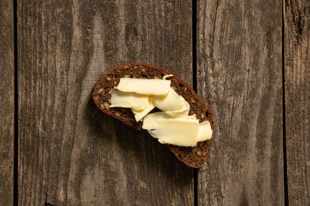 a piece of black bread with butter on an old wooden tableの写真素材