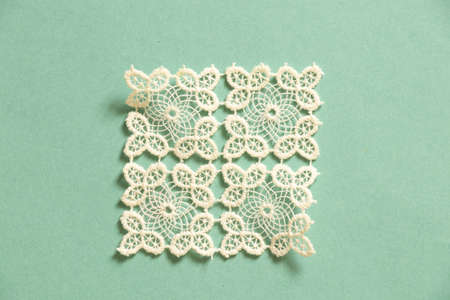 knitted white lace doily lies on a colored paper backgroundの写真素材