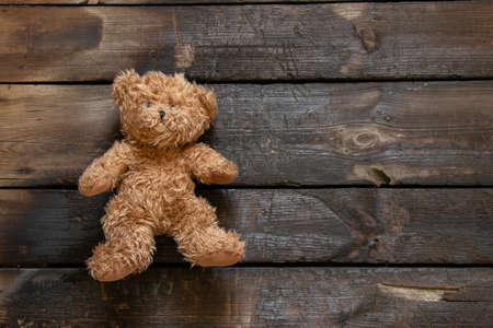 an old teddy brown bear lies on a burnt wooden floor alone, a child's toy on the floorの写真素材