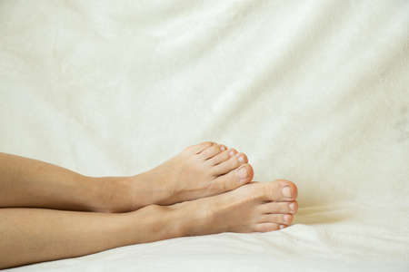 female legs lie on the bed barefoot, body parts, legs