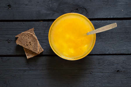 vegetable pea soup and a slice of black bread on a black wooden table in the kitchen, soup without meatの写真素材