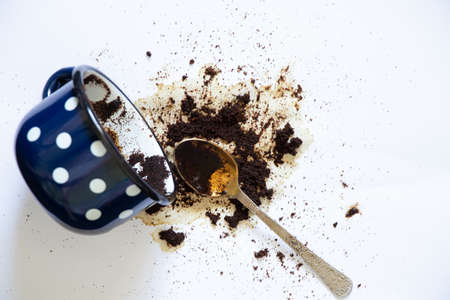 a cup with overturned coffee on a white background and a teaspoon lies next to it, spilled coffee on a white backgroundの写真素材