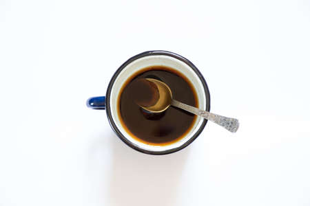 a cup with overturned coffee on a white background and a teaspoon lies next to it, spilled coffee on a white backgroundの写真素材