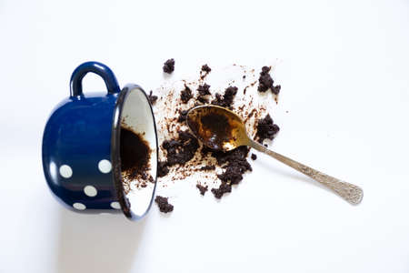 a cup with overturned coffee on a white background and a teaspoon lies next to it, spilled coffee on a white backgroundの写真素材