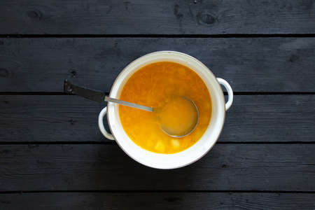 pea soup in a white saucepan on a black wooden table, homemade soup in the kitchen, no meat, vegan