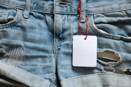 womens denim shorts with white blank paper price tag for text on table, price tag on shorts, place for priceの写真素材