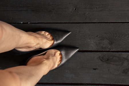 female legs in black high-heeled shoes on a black wooden floor, bottom view, women's shoesの写真素材