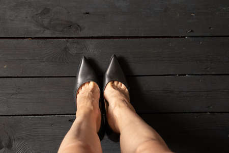 female legs in black high-heeled shoes on a black wooden floor, bottom view, women's shoesの写真素材