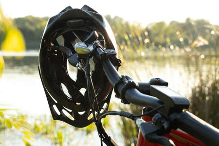 bicycle helmet on the handlebars of an e-bike at sunset in nature, cycling helmet on a bicycleの写真素材