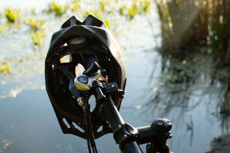 bicycle helmet on the handlebars of an e-bike at sunset in nature, cycling helmet on a bicycleの写真素材