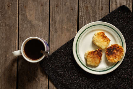 a cup of coffee and cheesecakes on a plate on an old wooden table, morning coffee with cheesecakes...