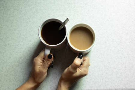 female hand holds a cup with coffee for breakfast on a light background, a cup of coffee