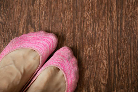 female legs in pink short socks on a wooden floor, legs in socksの写真素材