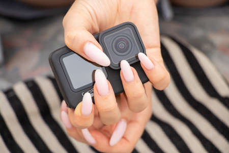 Ukraine Dnipro 08/05/2021 - Camera GoPro HERO 9 female hand holds on a striped background on the beach, action camera in handsのeditorial素材