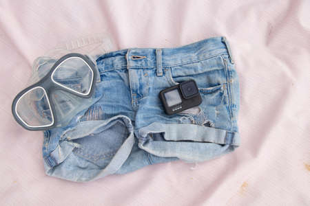 Ukraine Dnipro 08/05/2021 - GoPro HERO 9 camera lies on denim shorts and next to it is a diving mask on the beach, an action camera lies on jeans on the beachのeditorial素材