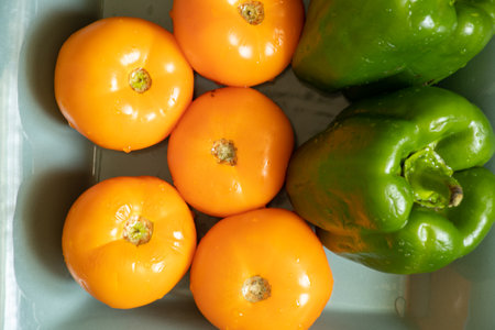 yellow tomatoes and selenium bell peppers lie on a plate on a black wooden table in the kitchen, ripe yellow tomatoes and peppersの写真素材